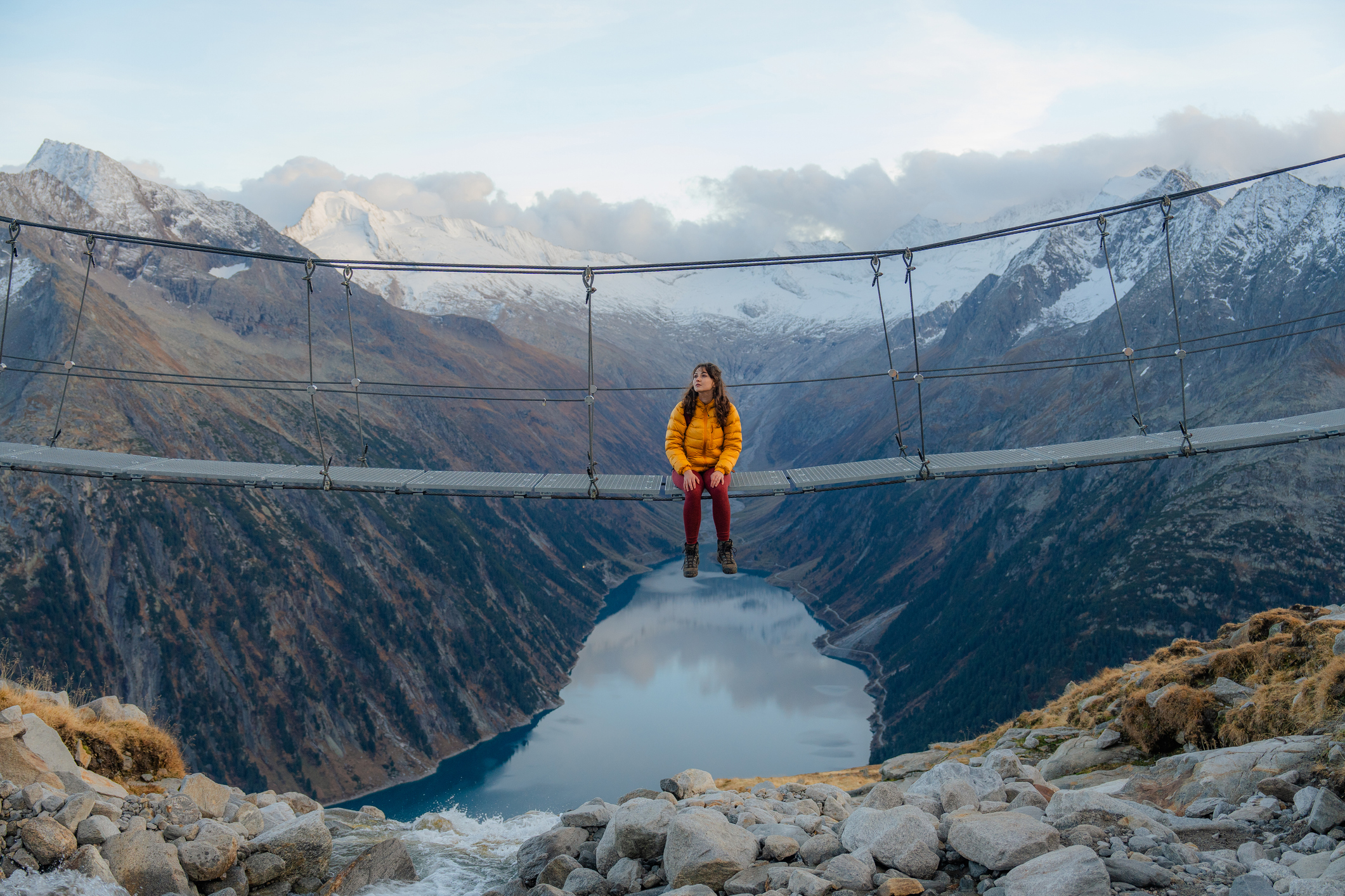 Young Caucasian woman on the bridge on the background of lake in Austrian Alps