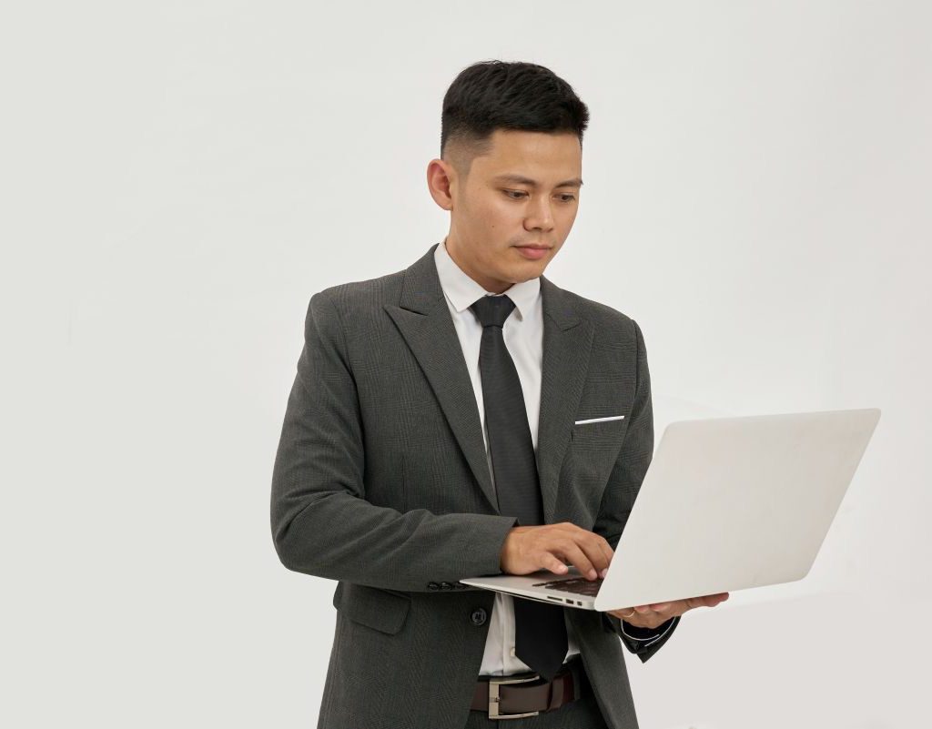 Geschäftsmann im Anzug arbeitet stehend an einem Laptop