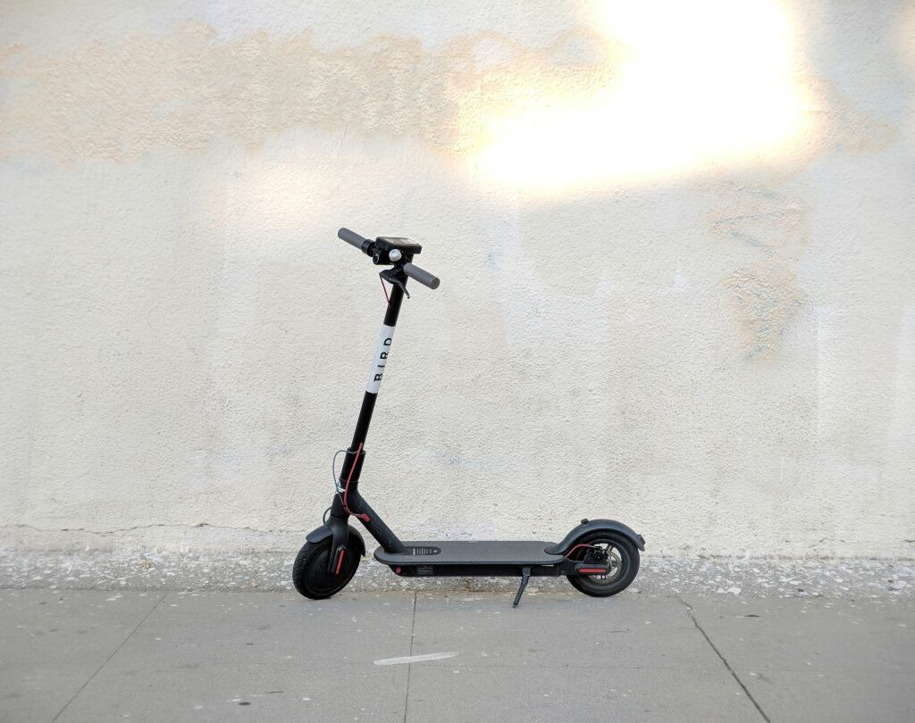 Elektroroller vor heller Wand im Freien