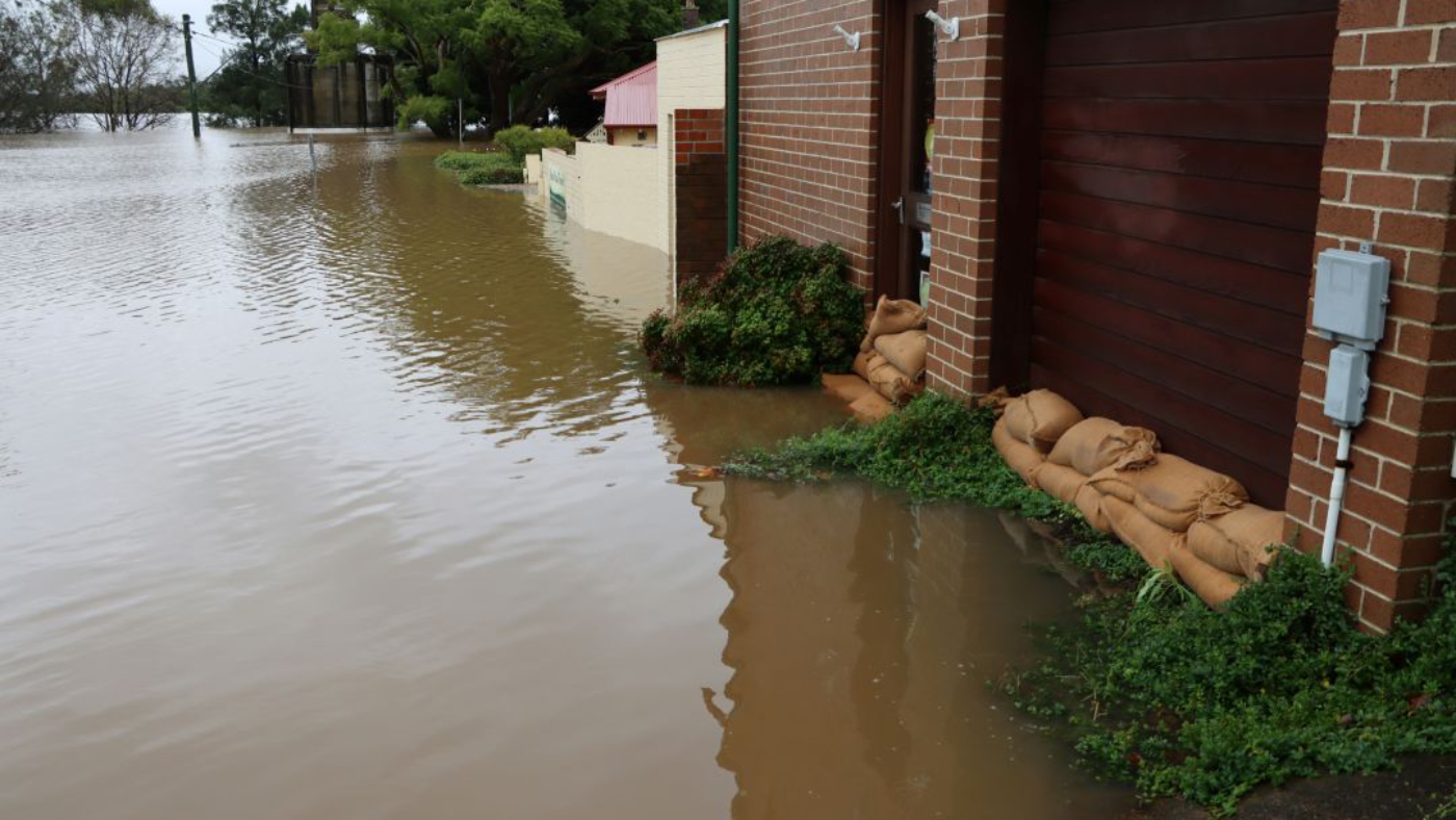 Hochwasser überflutet ein Haus, Sandsäcke vor der Tür.