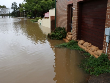 Hochwasser überflutet ein Haus, Sandsäcke vor der Tür.