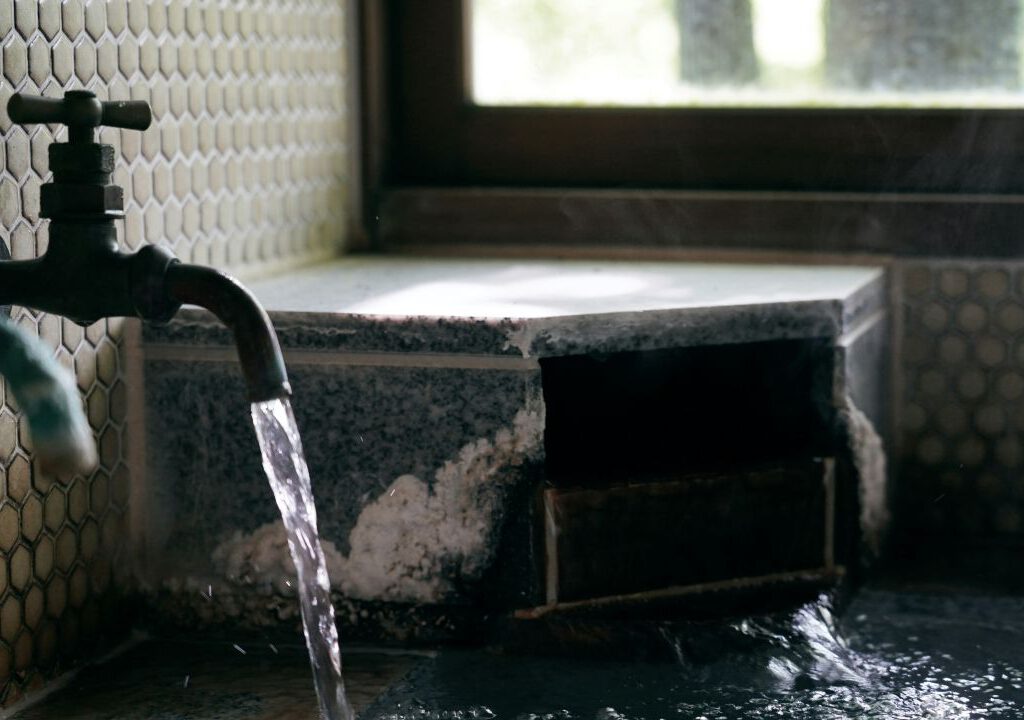 Wasser fließt aus einem Wasserhahn in ein Becken.