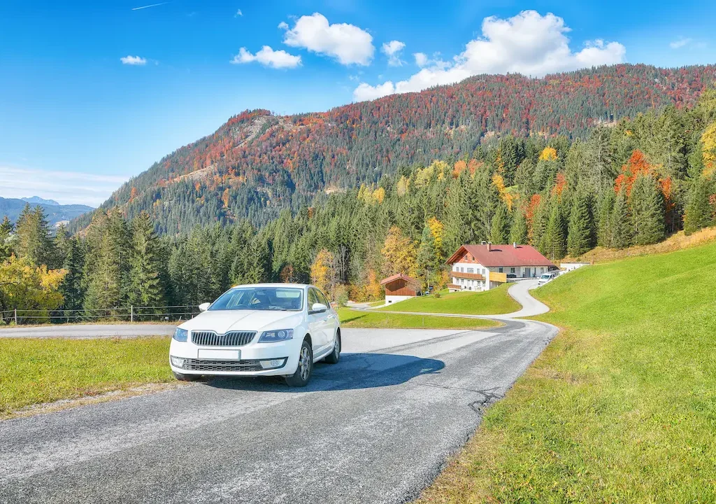 Auto auf Landstraße vor Berglandschaft im Herbst.