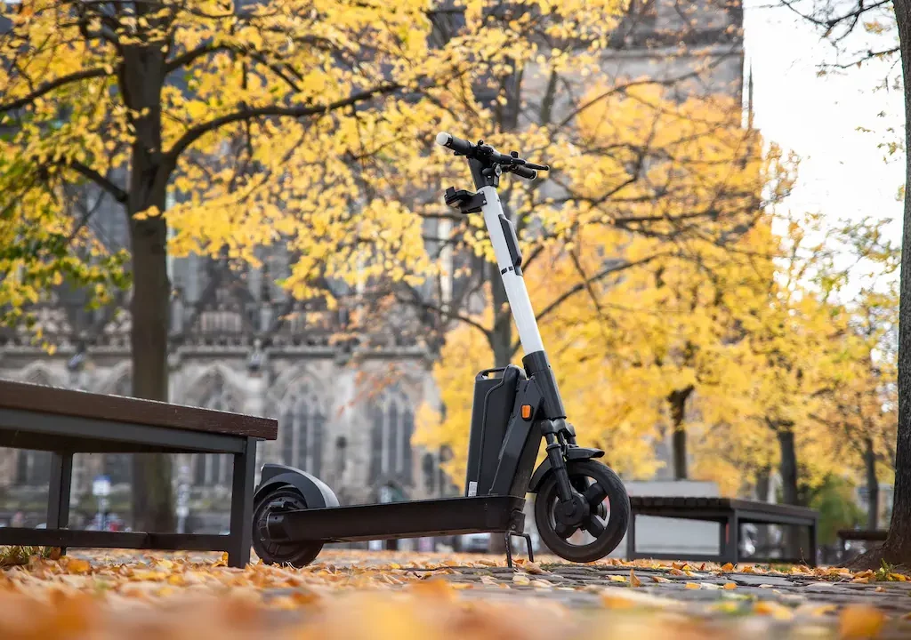 E-Scooter im Herbstpark neben einer Bank