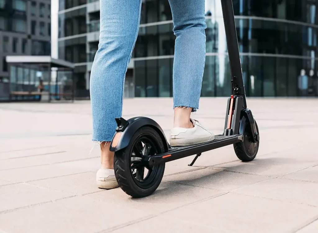 Person steht auf einem E-Scooter in moderner Umgebung