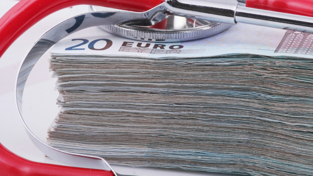 Rotes Stethoskop auf Stapel 20-Euro-Scheine – Symbol für Krankenversicherung und Gesundheitskosten