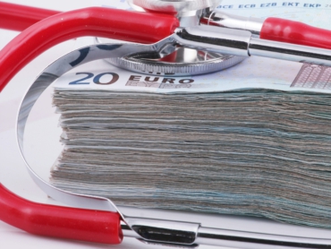 Rotes Stethoskop auf Stapel 20-Euro-Scheine – Symbol für Krankenversicherung und Gesundheitskosten